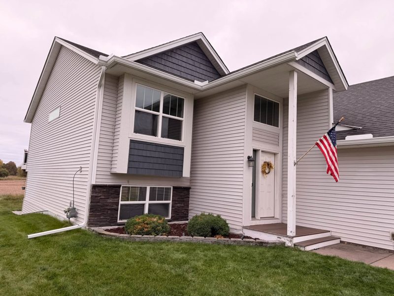 Split-level house with grey shake accents, white gutters and two white downspouts