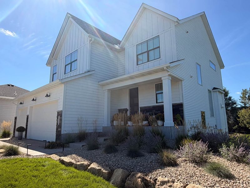 White two-story farmhouse-style house with white gutters along the roofline and downspouts